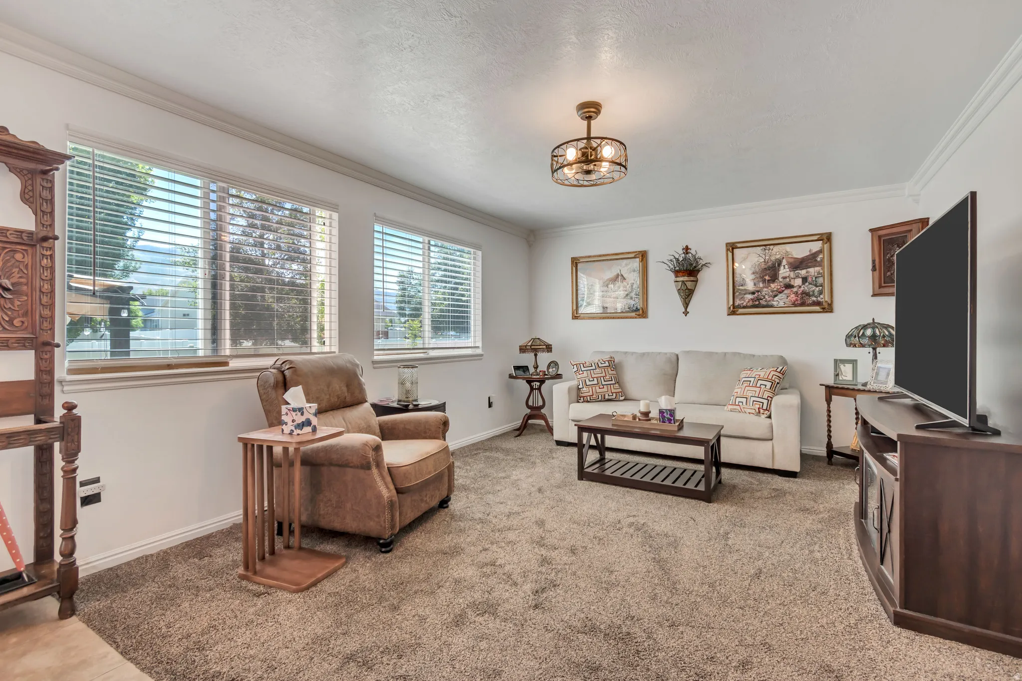 Carpeted living area featuring white walls, white trim, and crown molding