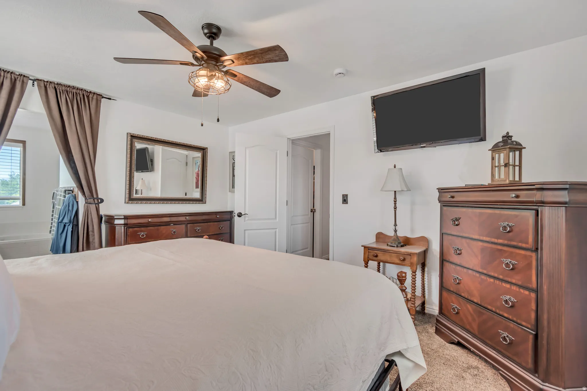 Room featuring a ceiling fan with integrated lighting, wall-mounted television, and neutral carpeting