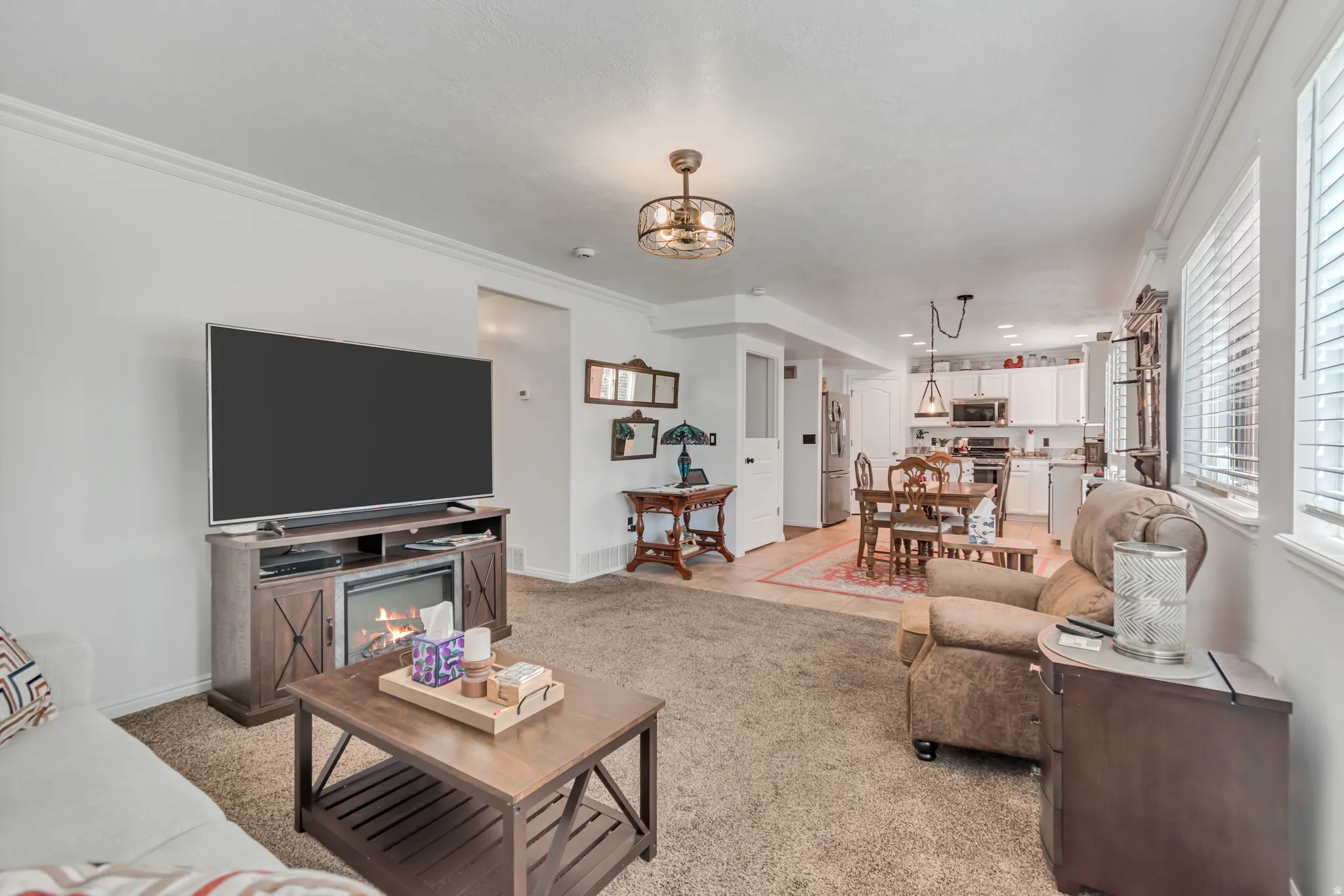 Open concept living area with carpet flooring, crown molding, and recessed lighting
