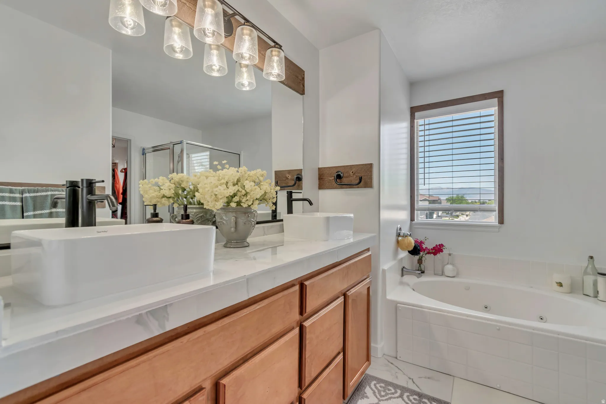 Double vanity featuring vessel sinks and matte black fixtures, complemented by a jetted tub with a tiled surround