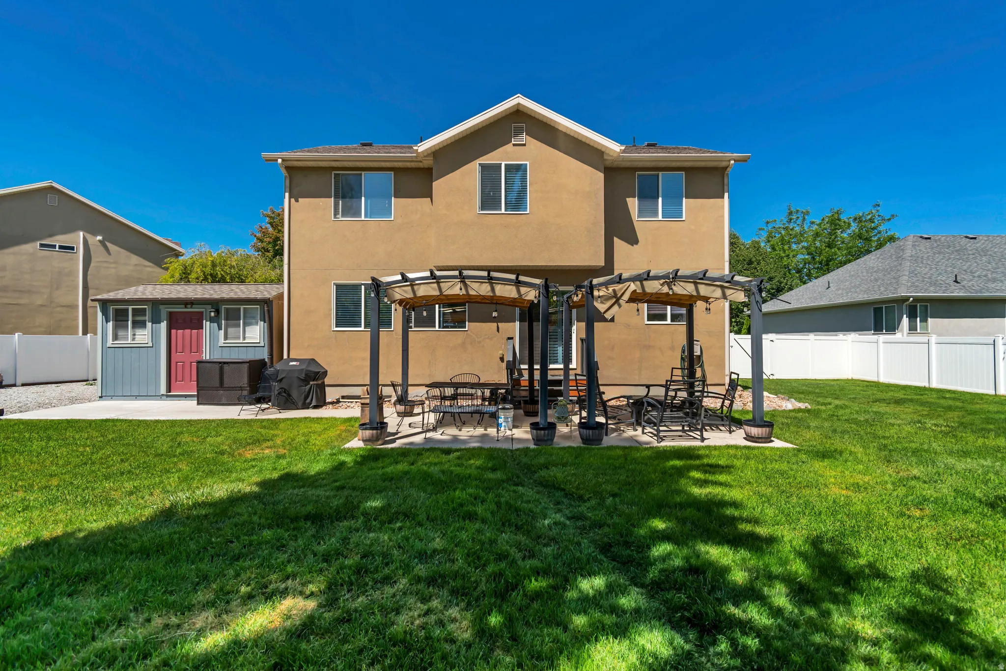 Expansive backyard featuring a lush lawn, a stucco exterior, and a two-story residence