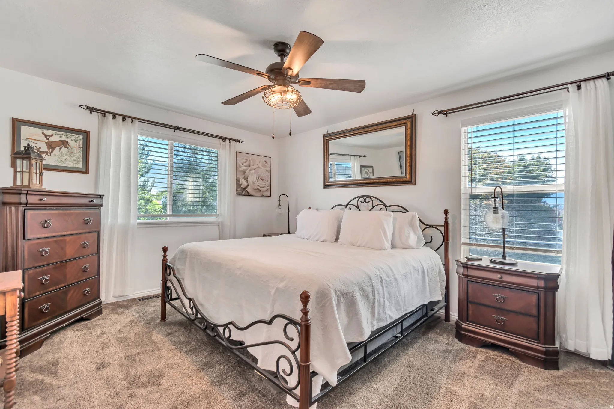 Spacious room featuring neutral carpet, white walls, and two large windows with blinds and sheer curtains