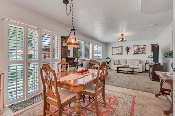 Dining area featuring ceramic tile flooring, a dark bronze pendant light fixture, and white plantation shutters on the sliding glass door