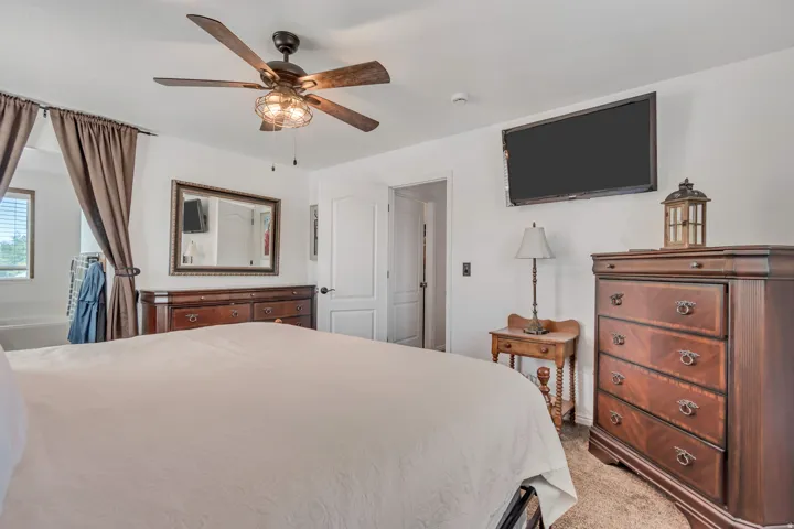 Room featuring a ceiling fan with integrated lighting, wall-mounted television, and neutral carpeting