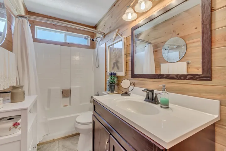 Bathroom featuring wood-paneled walls and a white tub/shower combination