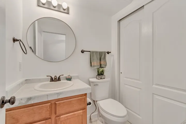 Bathroom vanity featuring a wood-finish cabinet, white countertop with integrated sink, and an oval mirror
