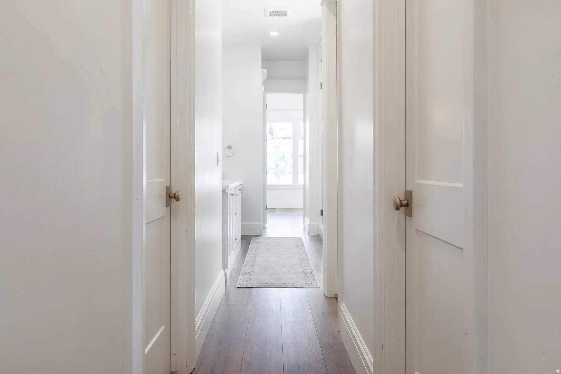 Hallway featuring wood-finish flooring, white paneled doors, and recessed lighting
