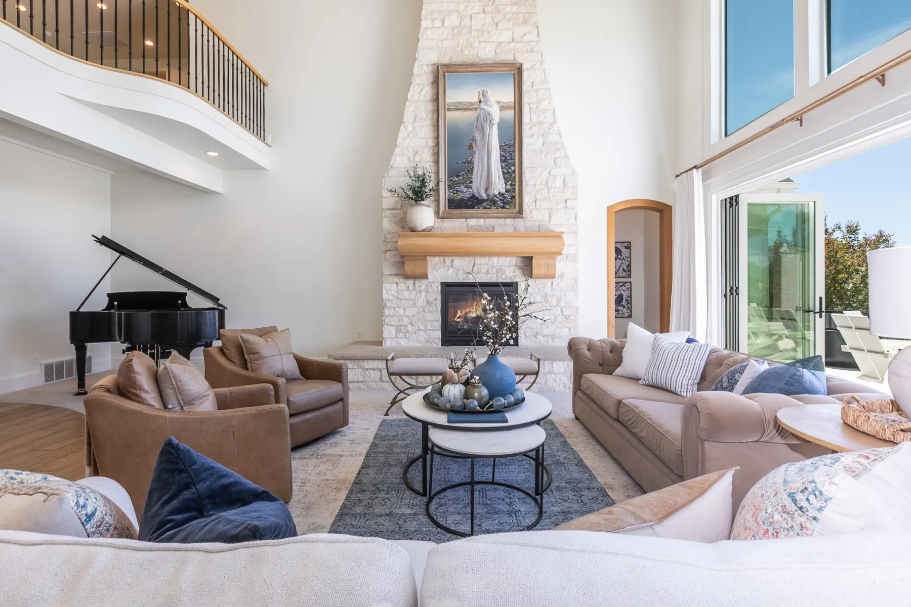 Great room featuring a floor-to-ceiling stone fireplace with a wood mantle, soaring ceilings, and expansive floor-to-ceiling windows