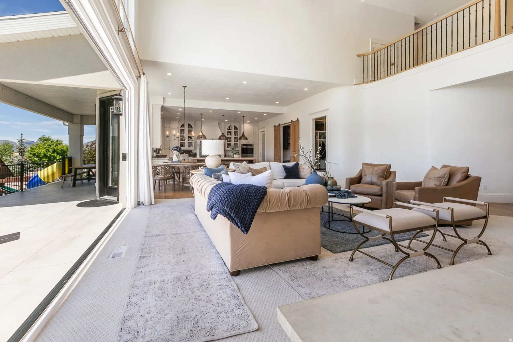 Expansive living area with high ceilings, wood-finish flooring, and a second-story balcony featuring wood and iron railings