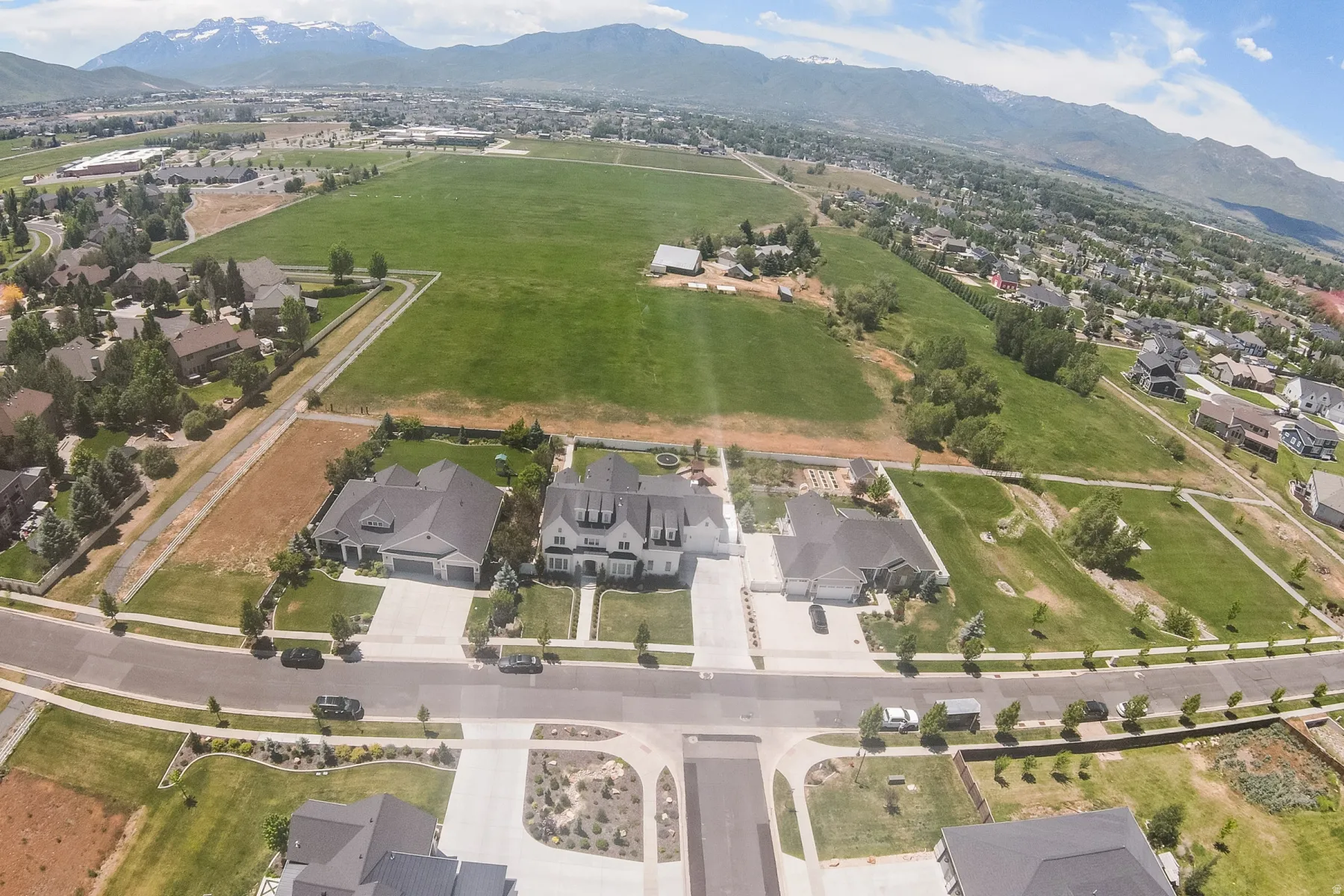 Aerial perspective highlighting a residential community with contemporary homes, expansive green spaces, and mountain backdrops