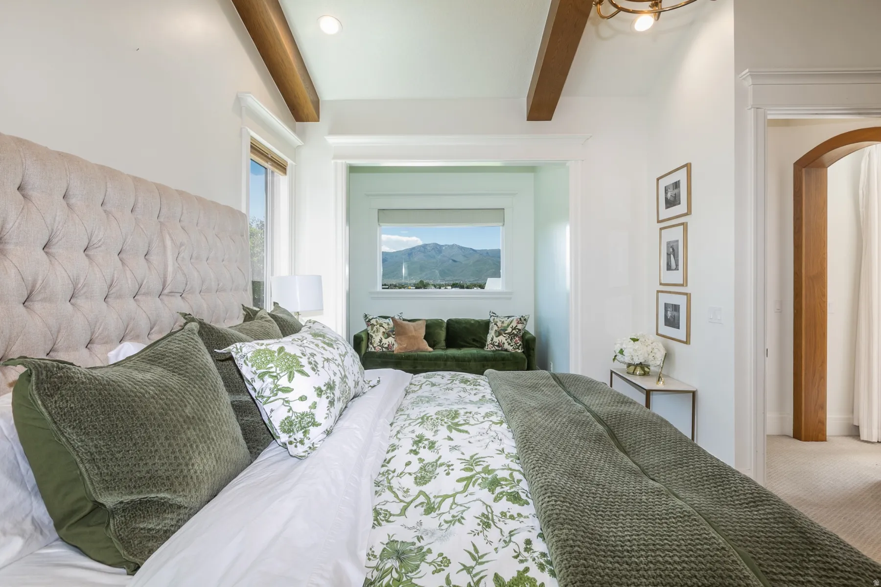 Bright room featuring high ceilings with exposed wood beams, a windowed alcove with mountain scenery, an arched doorway, and recessed lighting