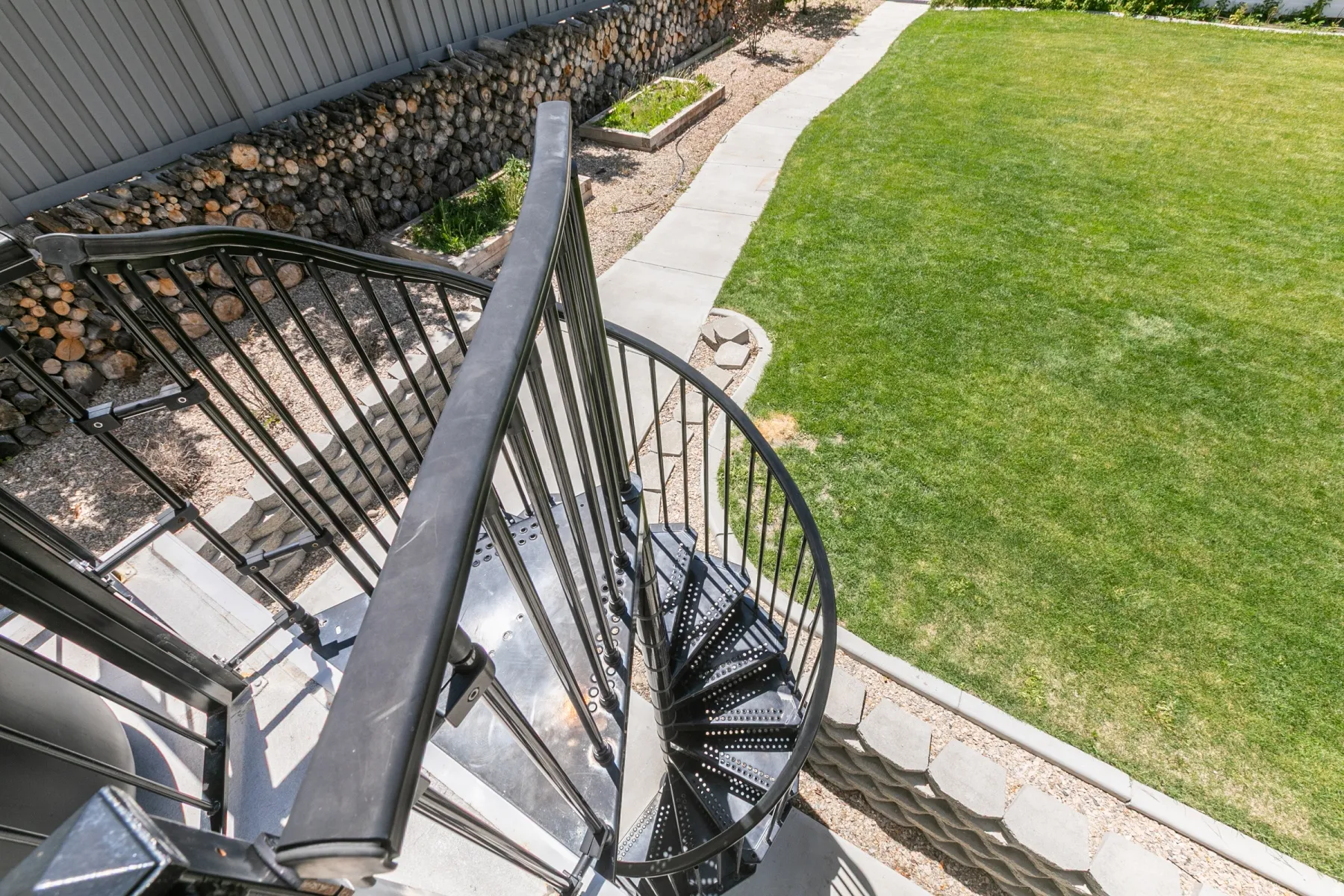 Black metal spiral staircase providing access to the expansive green lawn