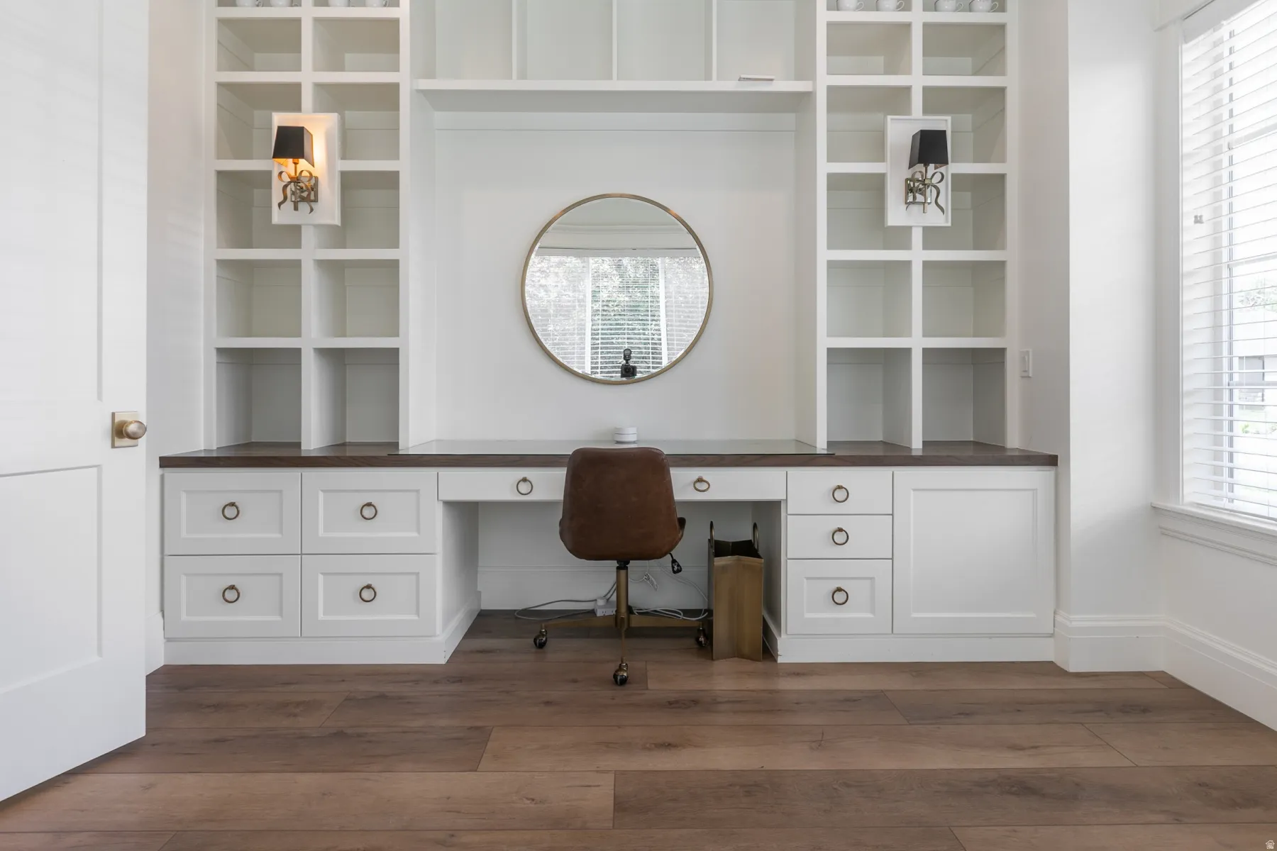 Integrated desk with a dark wood-finish countertop, crisp white cabinetry, and ring pull hardware