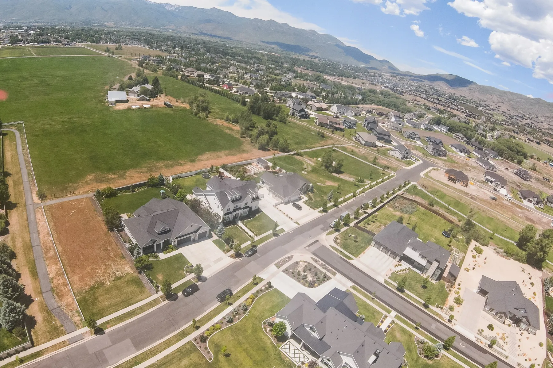 Expansive suburban landscape featuring residential properties, paved streets, and a distant mountain range under a partly cloudy sky