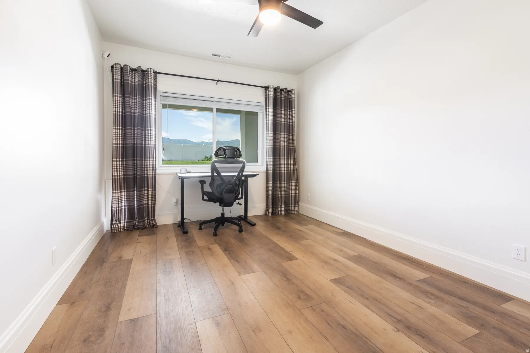 Spacious room featuring wood-finish flooring, white walls, and bright white trim