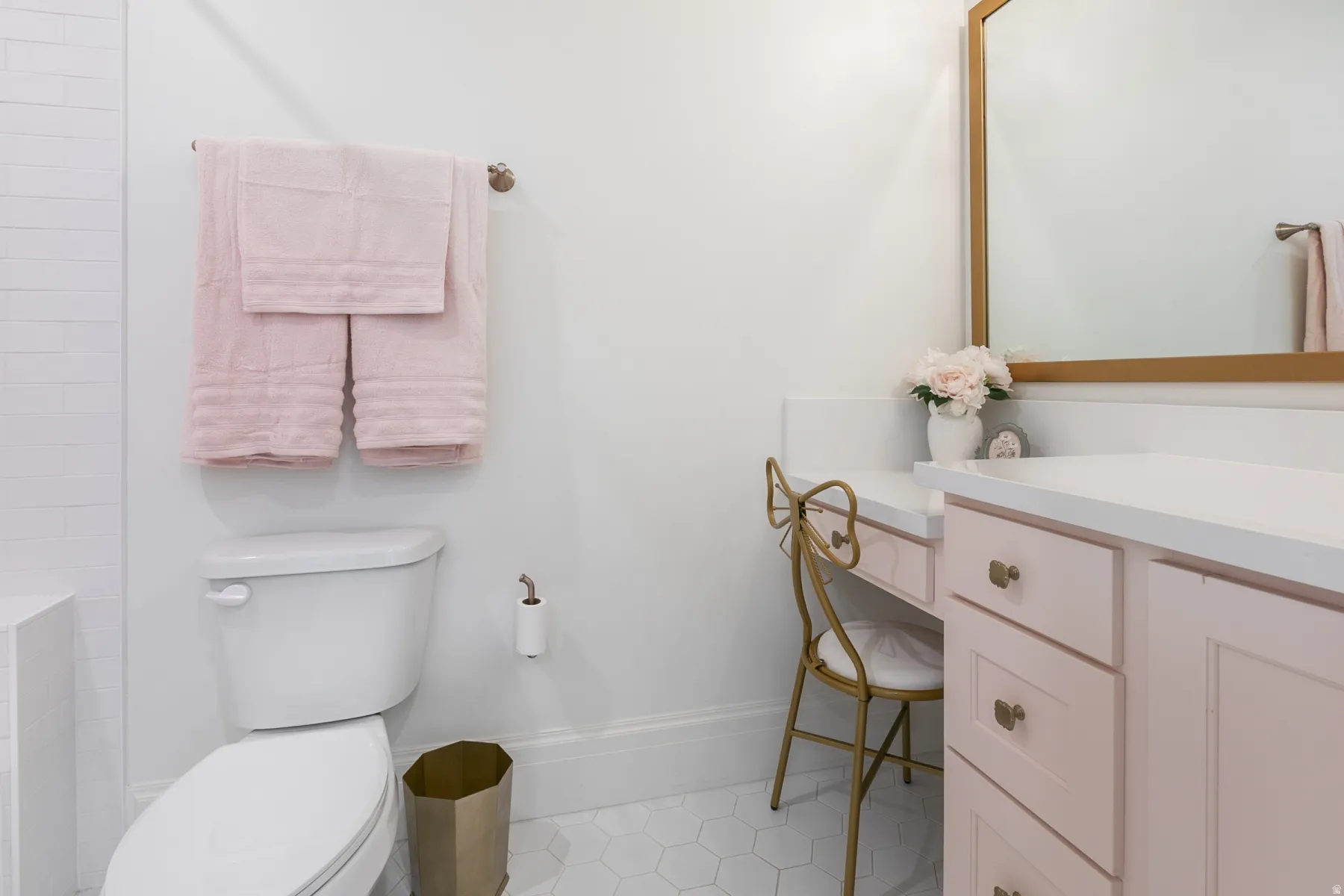 Bathroom featuring a white toilet, hexagonal floor tiles, a light pink vanity with white countertops, a built-in makeup vanity, and a framed mirror