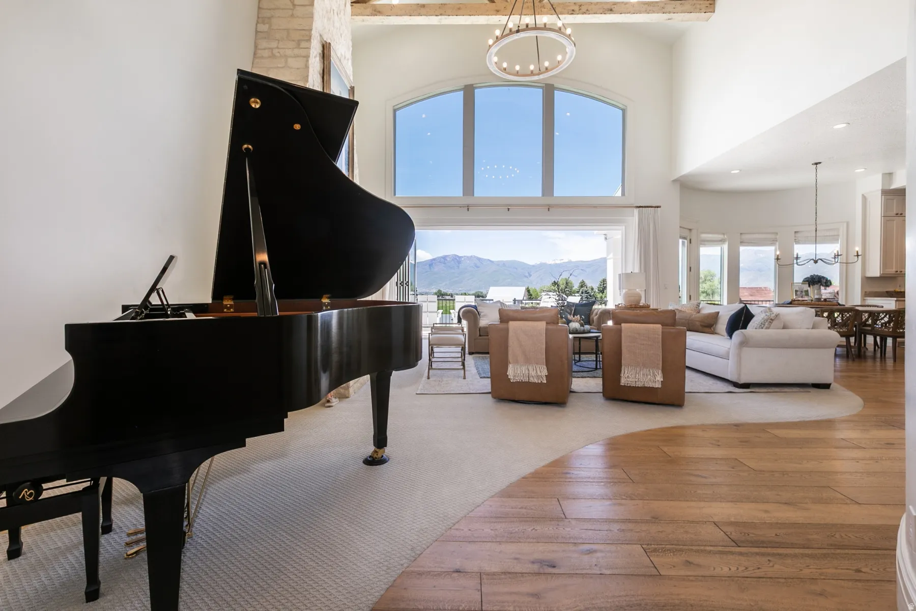 Grand living space featuring a soaring vaulted ceiling, arched window, and exposed wooden beam accents