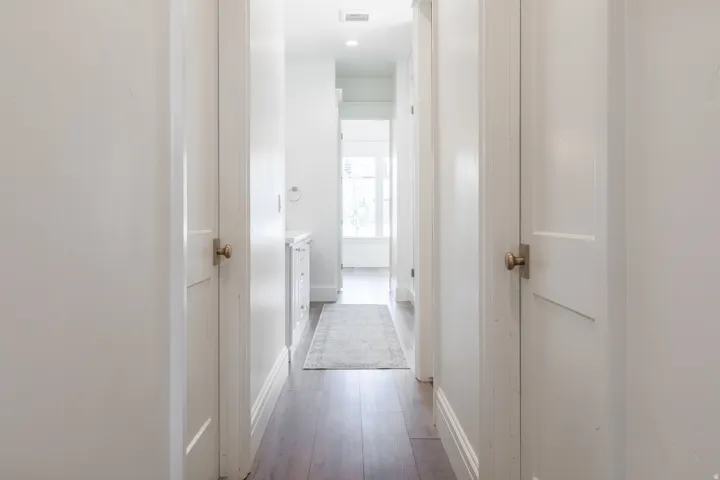 Hallway featuring wood-finish flooring, white paneled doors, and recessed lighting