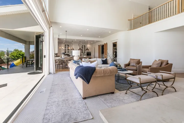 Expansive living area with high ceilings, wood-finish flooring, and a second-story balcony featuring wood and iron railings