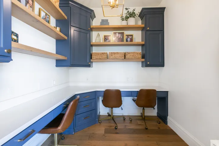 Built-in office space featuring rich wood-finish flooring, white countertops, and deep blue cabinetry