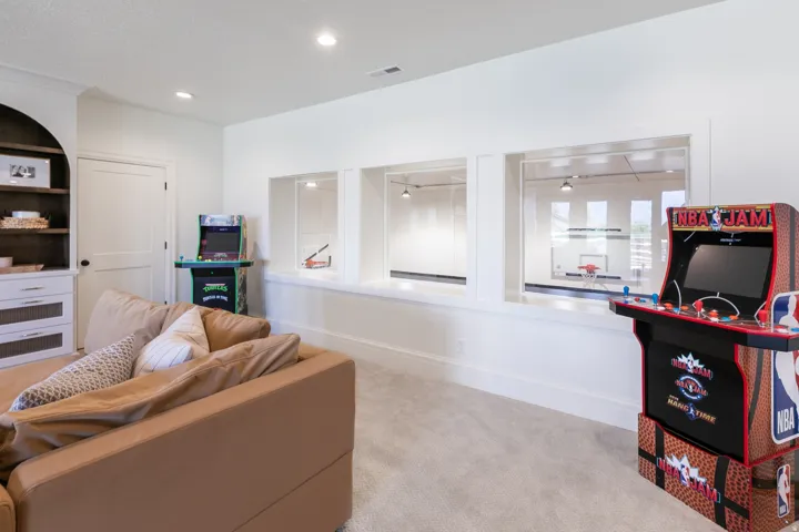 Recreational space featuring recessed lighting, light-toned carpeting, and a built-in shelving unit with dark wood-finish shelves and white cabinetry