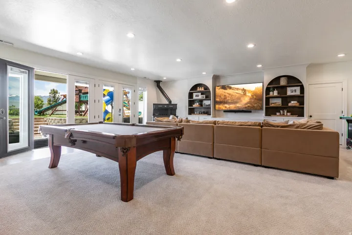 Spacious recreation area featuring plush carpeting, recessed lighting, and built-in shelving with arched accents
