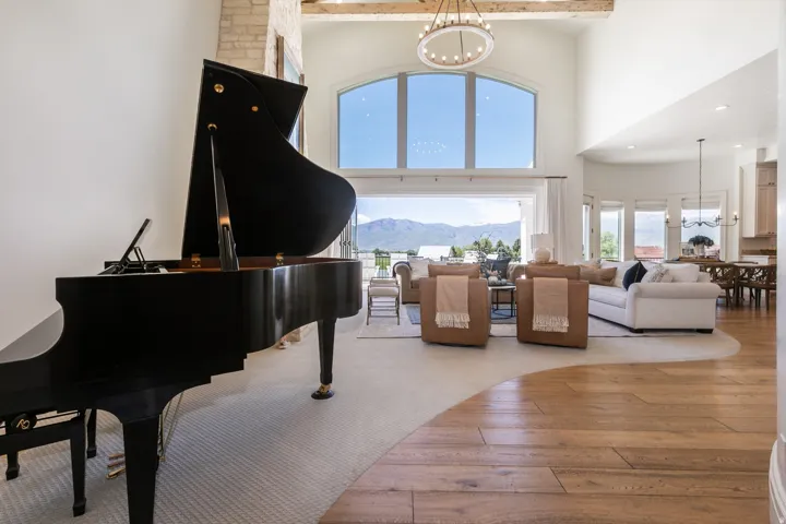 Grand living space featuring a soaring vaulted ceiling, arched window, and exposed wooden beam accents