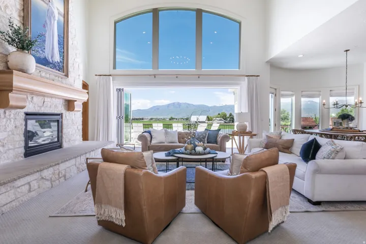 Spacious living area featuring a stone-clad fireplace with a wood mantel, vaulted ceilings, and a large arched transom window