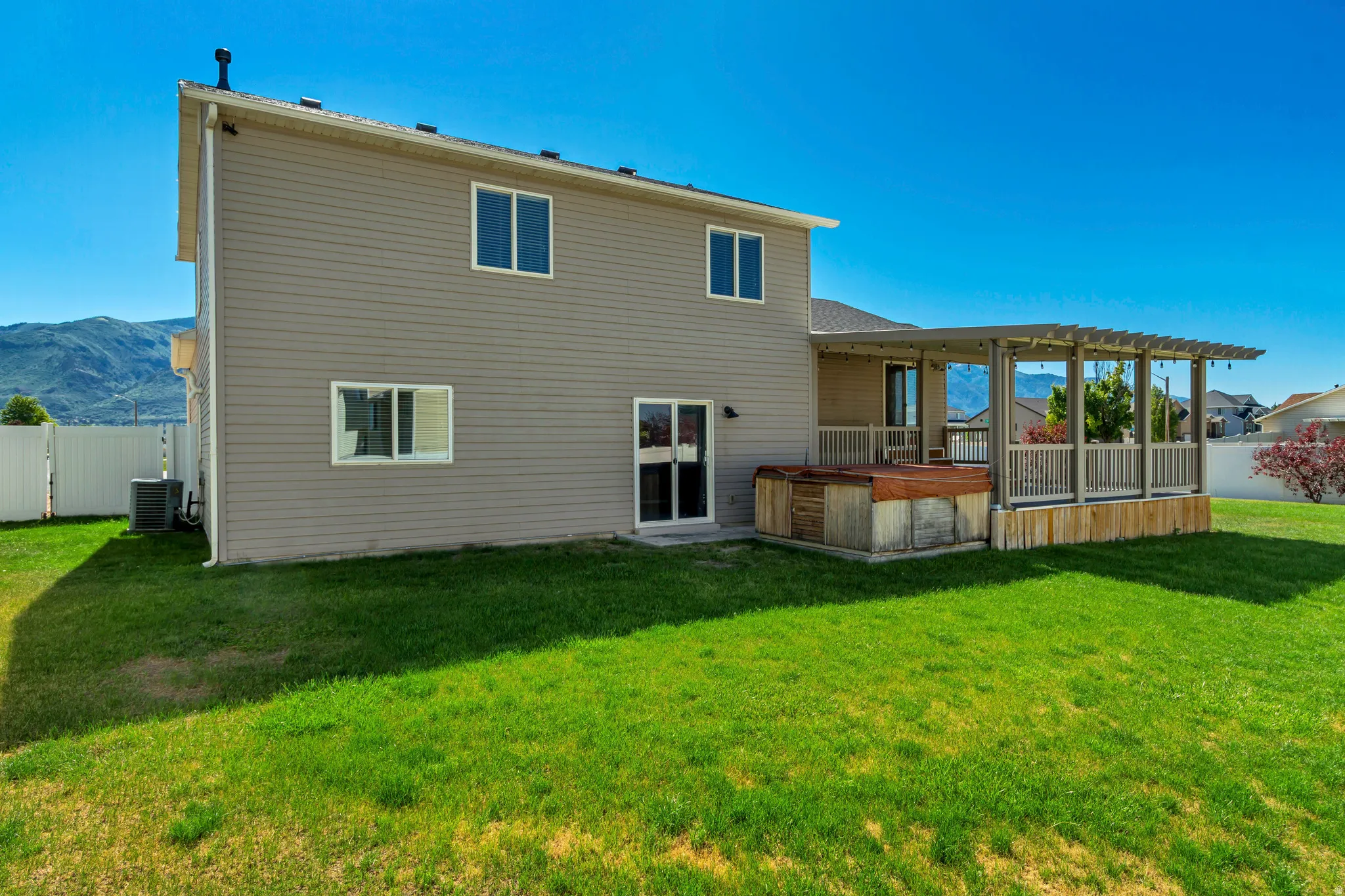 Expansive green lawn with a two-story exterior featuring tan siding