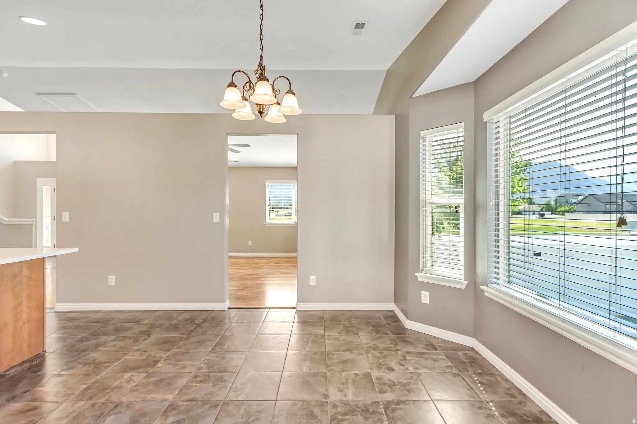 Spacious dining area featuring large windows, a decorative chandelier, and durable tile flooring