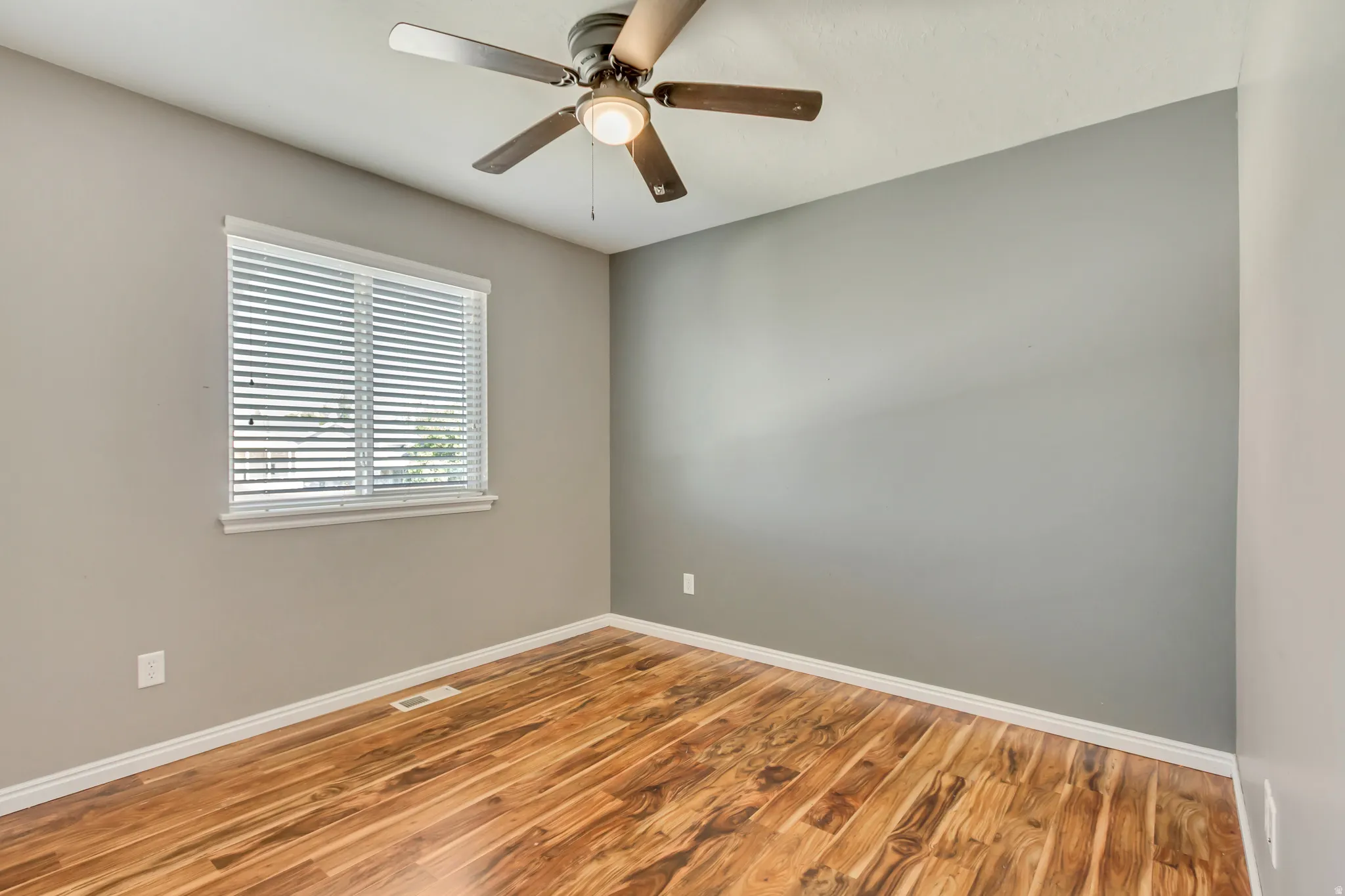 Room featuring wood-finish flooring, a window with blinds, a ceiling fan with integrated lighting, and neutral wall paint