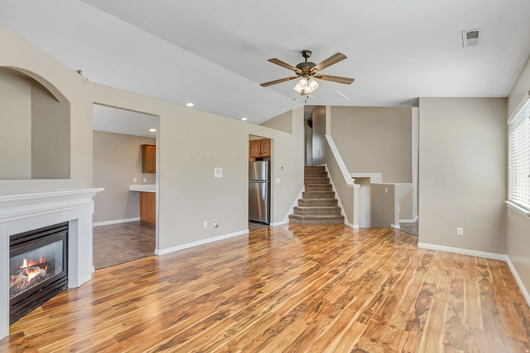 Spacious living area featuring wood-finish flooring, a white mantel fireplace, recessed lighting, and a ceiling fan