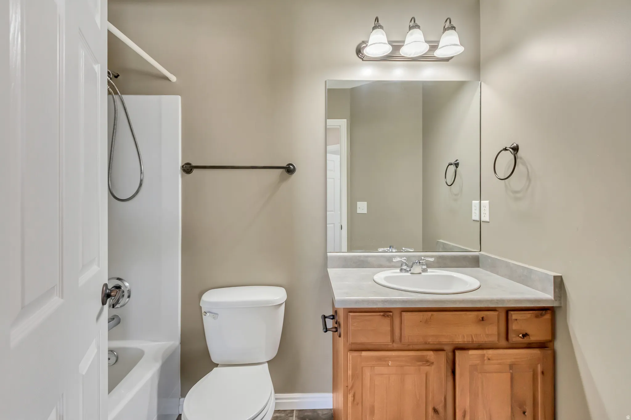 Bathroom featuring a vanity with a light wood-finish cabinet, integrated sink, and a large mirror