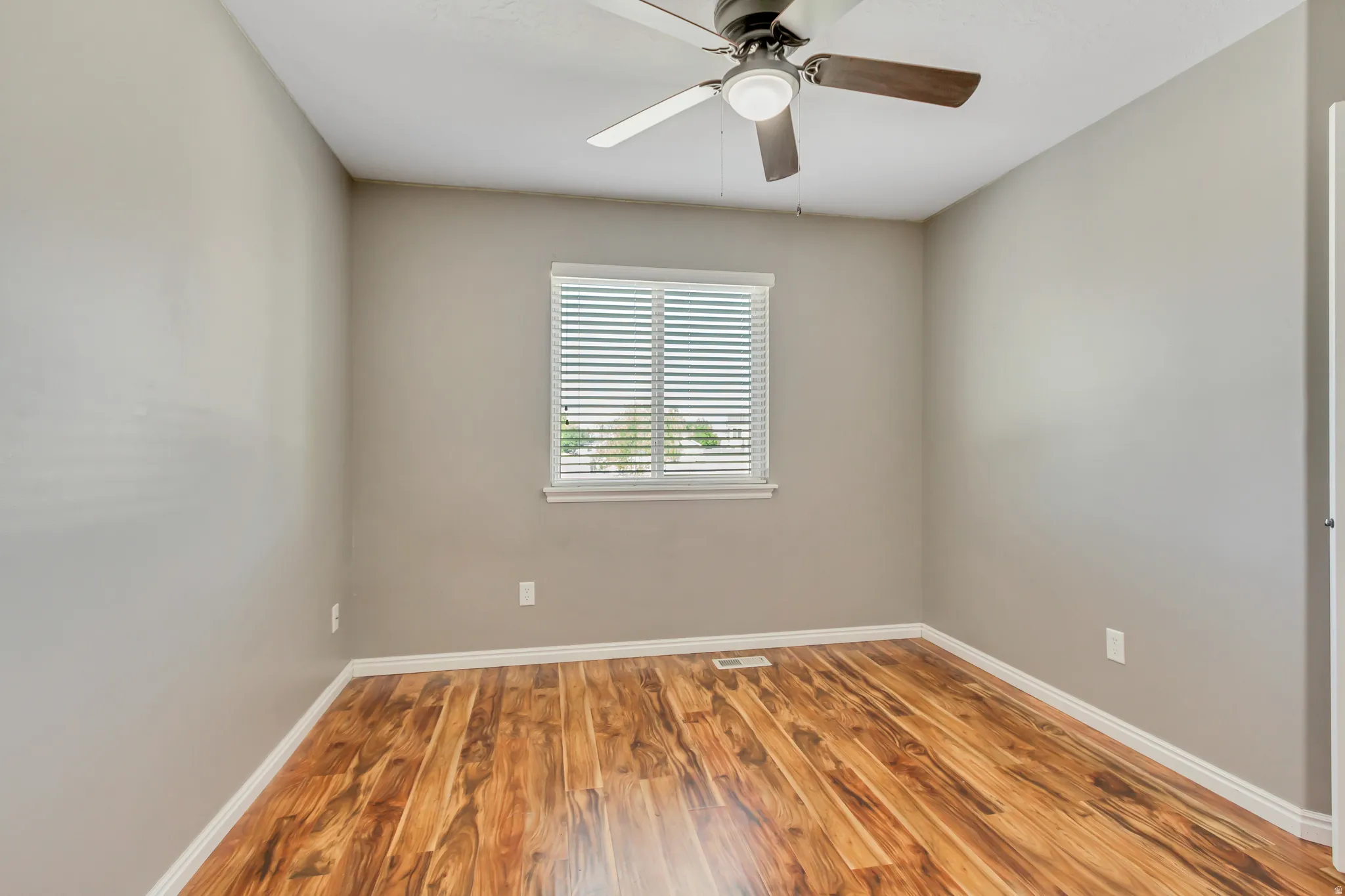 Room featuring wood-finish flooring, neutral wall paint, and white baseboards