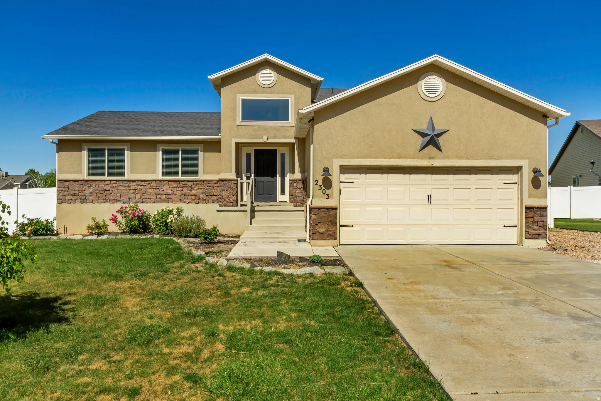 Stucco exterior featuring stone veneer accents, a two-car garage, and a concrete driveway