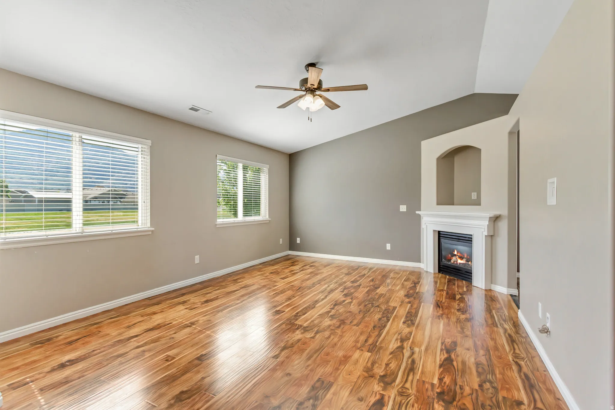 Spacious interior with wood-finish flooring, a vaulted ceiling, and a ceiling fan