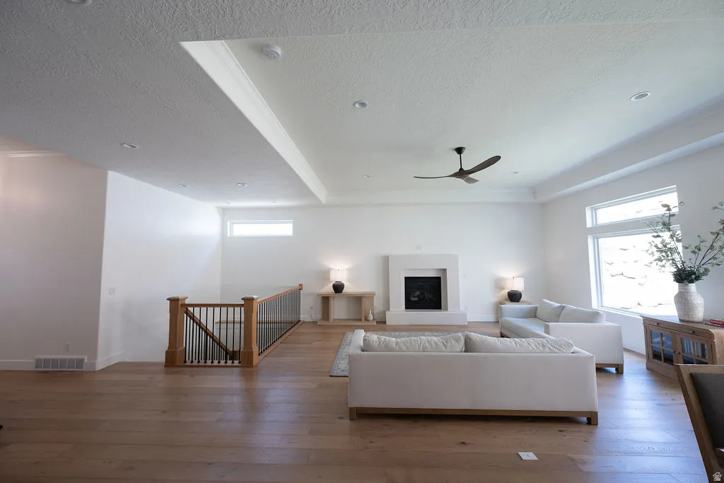 Spacious living area featuring wood-finish flooring, a contemporary fireplace, and a tray ceiling with recessed lighting