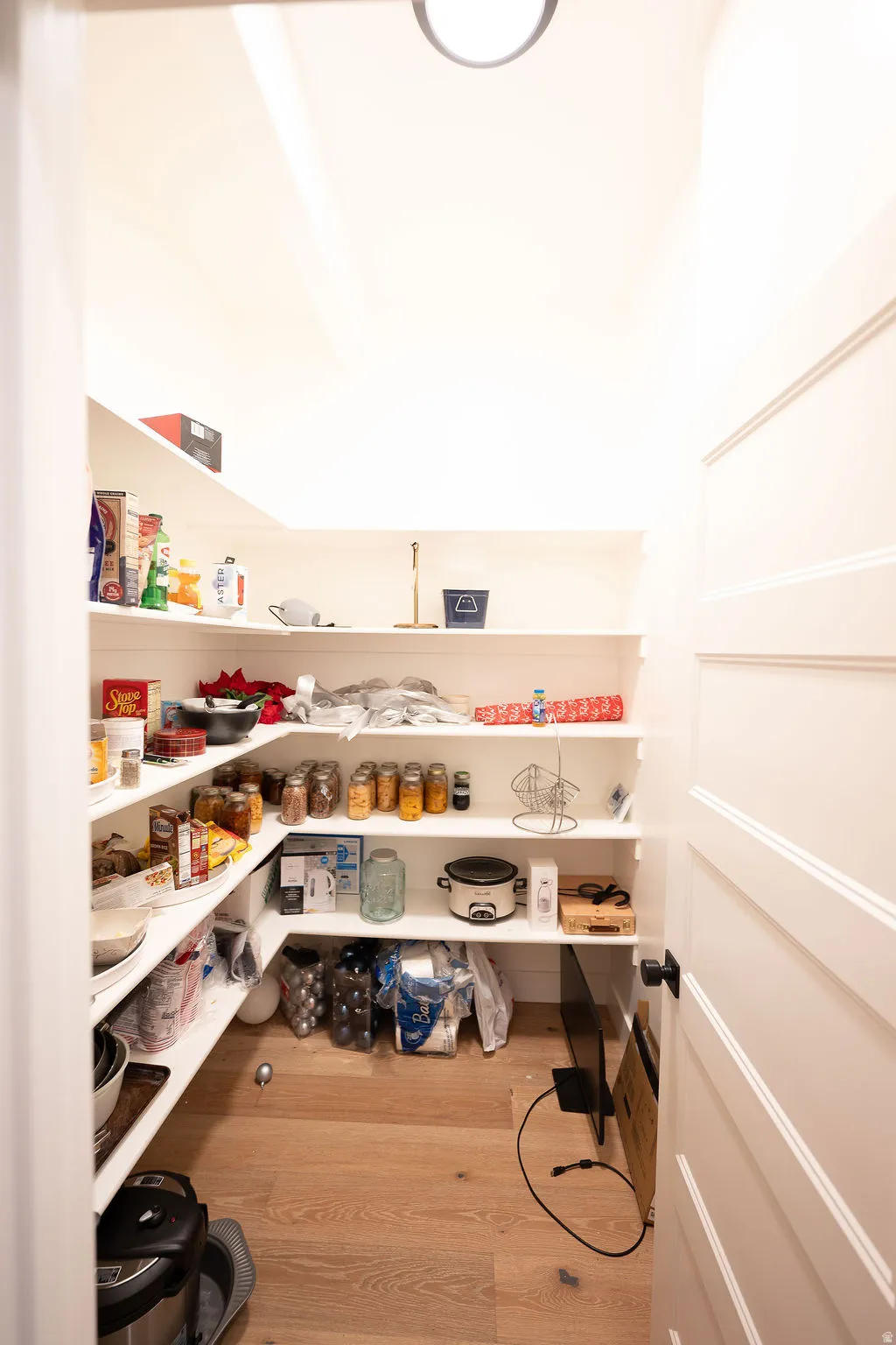 Walk-in pantry featuring light wood-finish flooring, recessed lighting, white walls, and built-in shelving