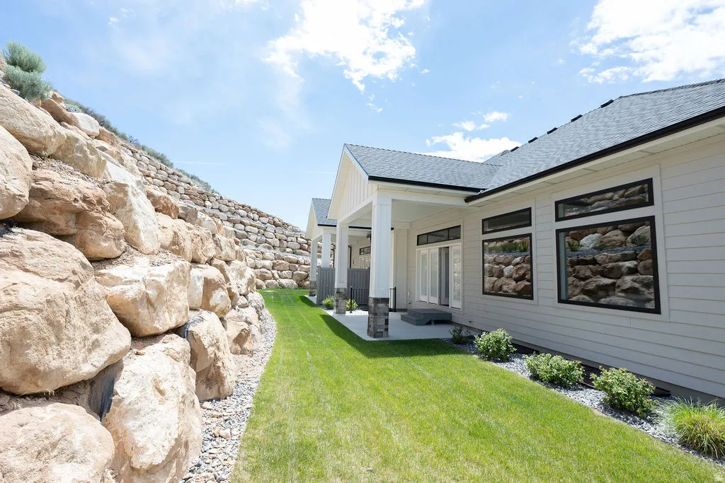 Exterior featuring light-colored horizontal siding, black-framed windows, and a covered patio with white columns