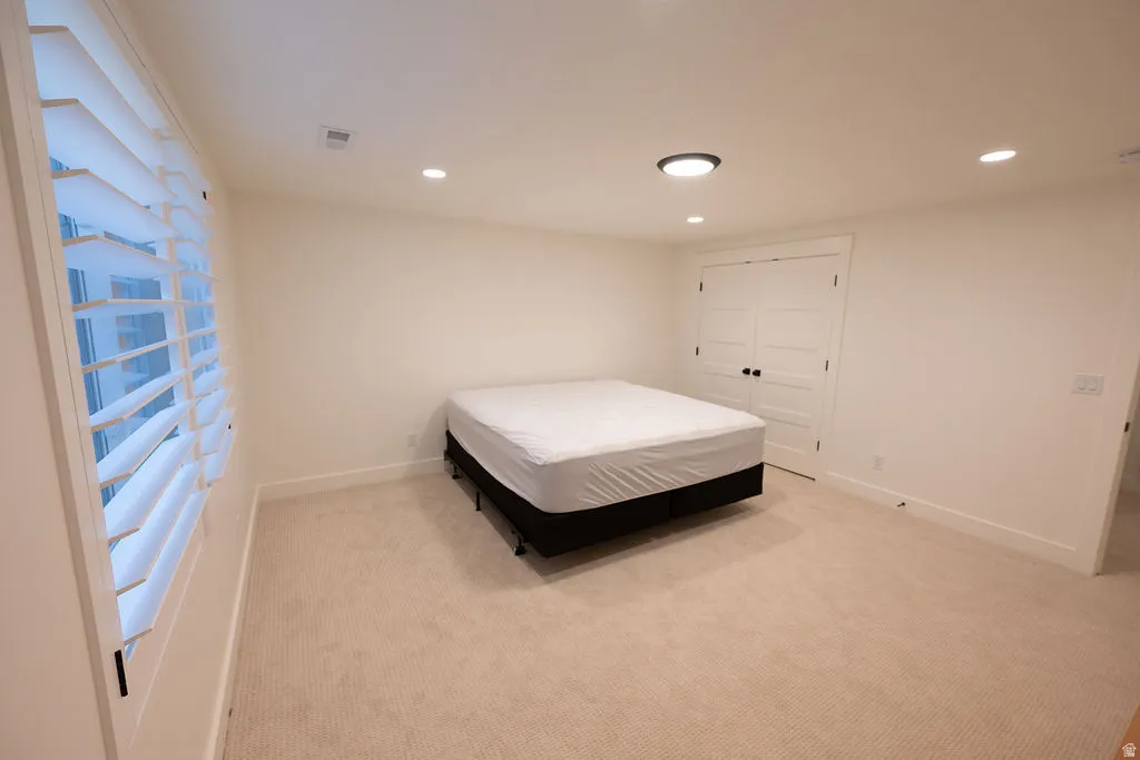 Neutral-toned room with plush carpeting, recessed lighting, and a modern flush-mount ceiling fixture