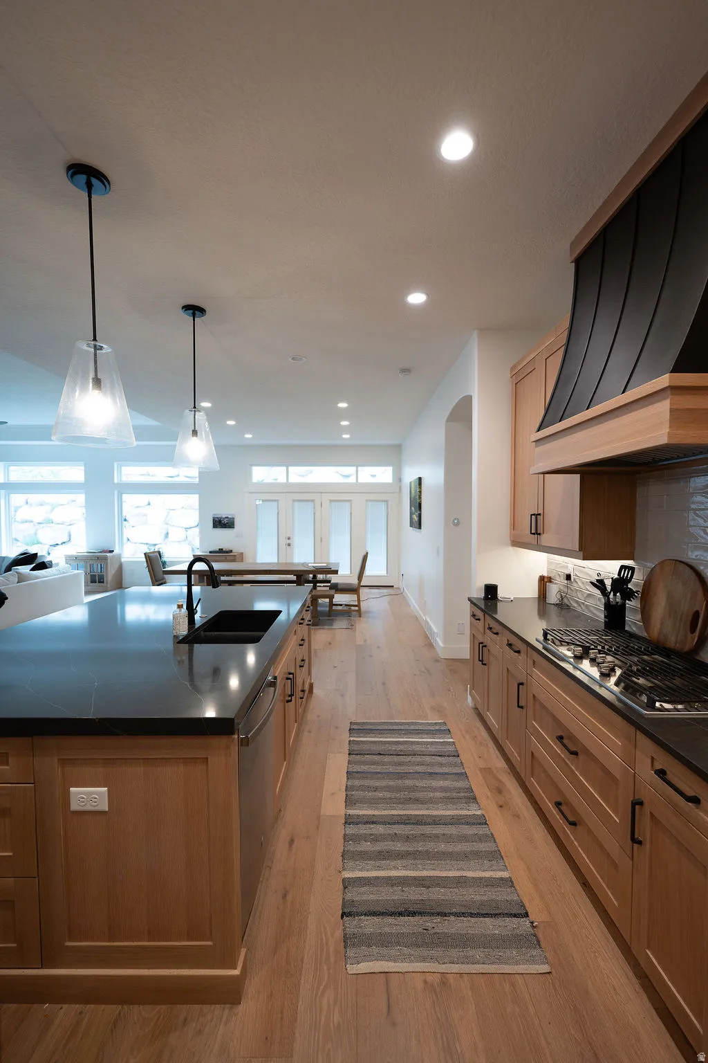 Open-concept kitchen featuring wood-finish flooring, recessed lighting, and a kitchen island with dark countertops