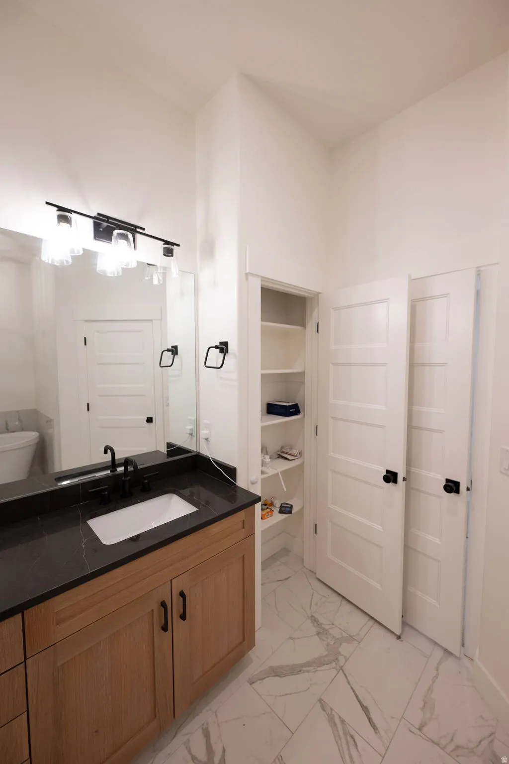 Bathroom vanity featuring a dark countertop, undermount sink, and black faucet