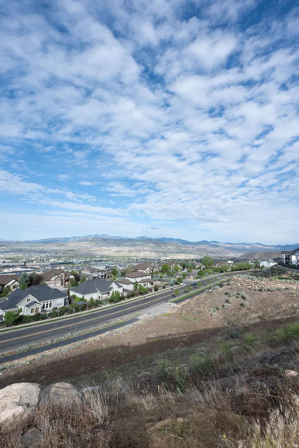 Expansive land parcel featuring natural ground cover, scattered rocks, and distant mountain ranges