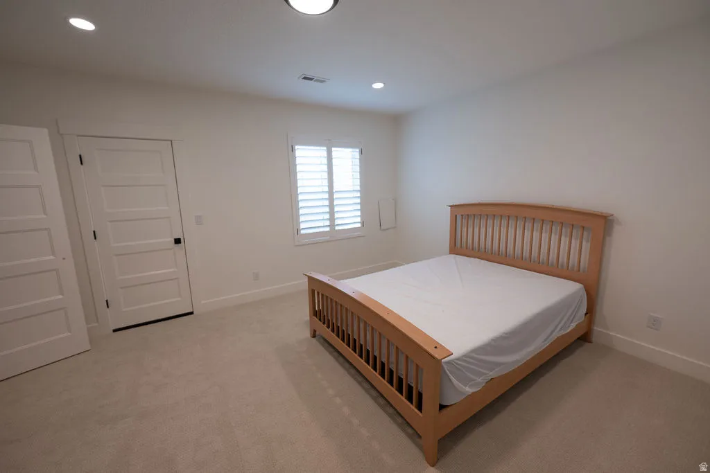 Carpeted room featuring white walls, a single window with white plantation shutters, and two five-panel interior doors with black hardware