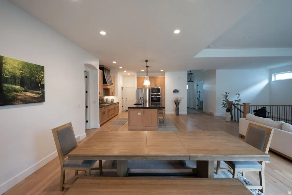 Open-concept living space featuring wood-finish flooring, recessed lighting, and a kitchen with stainless steel appliances, dark countertops, and wood cabinetry