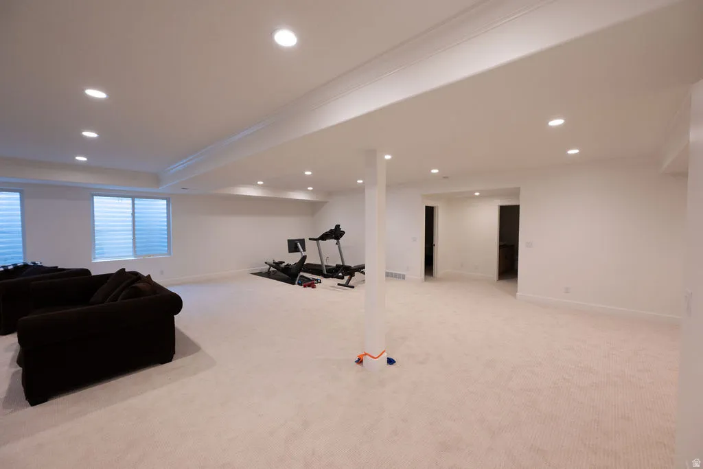 Spacious lower-level room featuring recessed lighting, a neutral carpeted floor, white walls, and two visible window wells