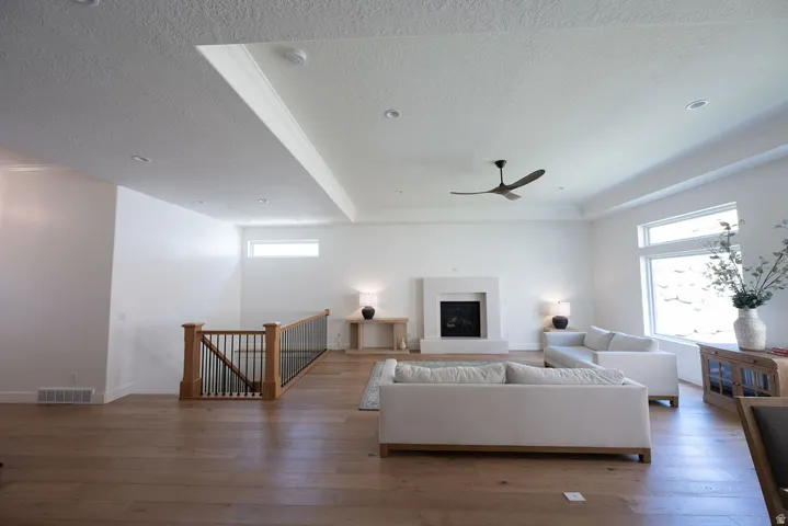 Spacious living area featuring wood-finish flooring, a contemporary fireplace, and a tray ceiling with recessed lighting