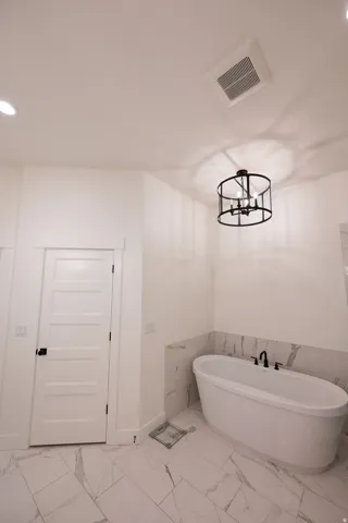 Freestanding soaking tub with matte black fixtures, set against a tiled accent wall