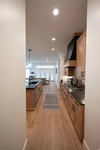 Kitchen featuring wood cabinetry, dark countertops, a gas range, and a large central island with an integrated sink