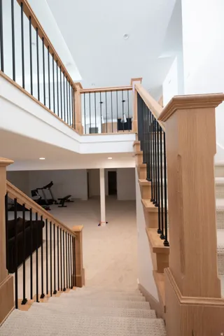 Multi-level interior featuring a staircase with carpeted treads and wood-finish handrails, complemented by black iron balusters